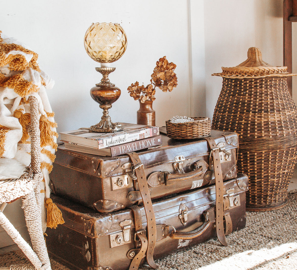 Vintage boho bohemian home decor style featuring sheepskins, vintage suitcase, cane basket and tassle throw