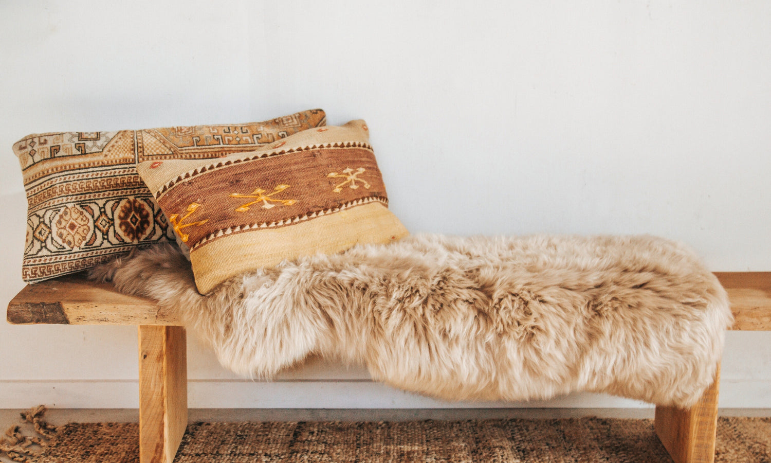 Gorgeous neutral boho sheepskin on wooden bench with Kilim cushions