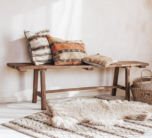 vintage reclaimed rustic wooden boho style bench seat with kilim cushions and sheepskin