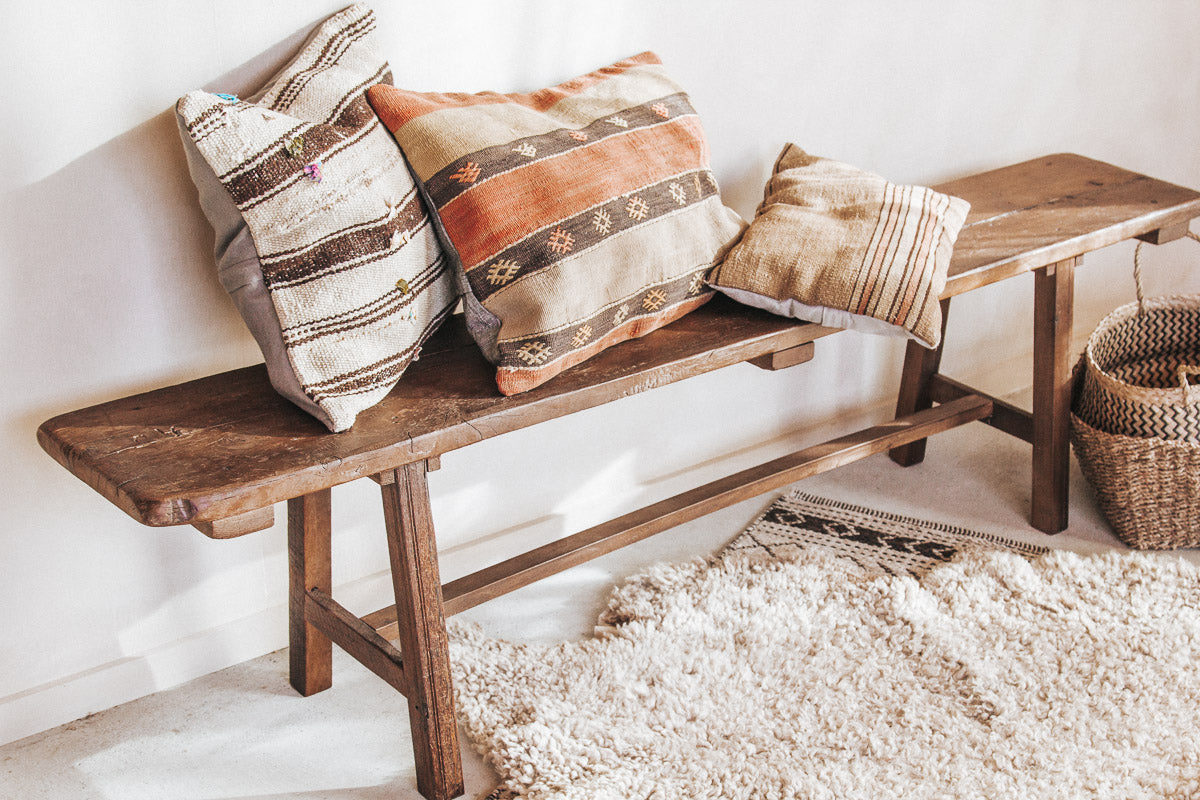 vintage reclaimed rustic wooden boho style bench seat with kilim cushions and sheepskin