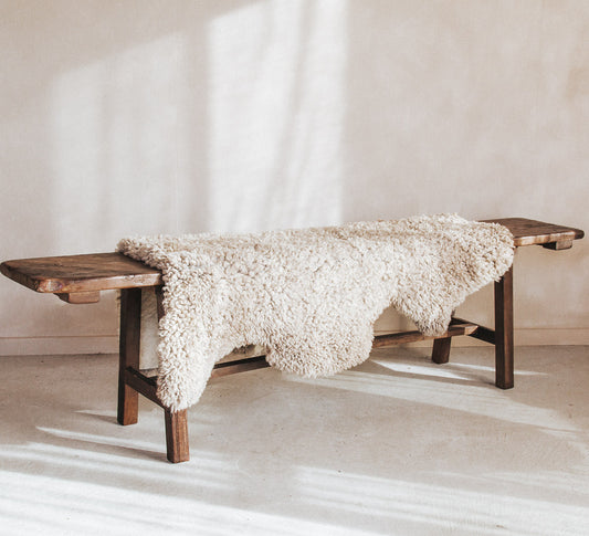 vintage reclaimed rustic wooden boho style bench seat with kilim cushions and sheepskin