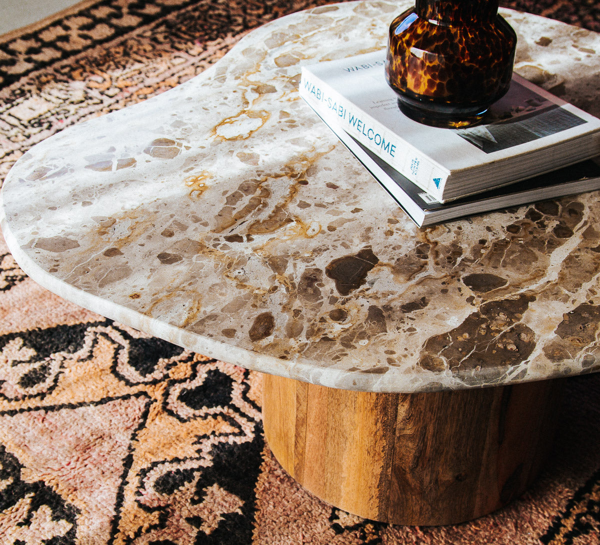 boho designer avi marble coffee table in an organic shape with a round curved solid wood base
