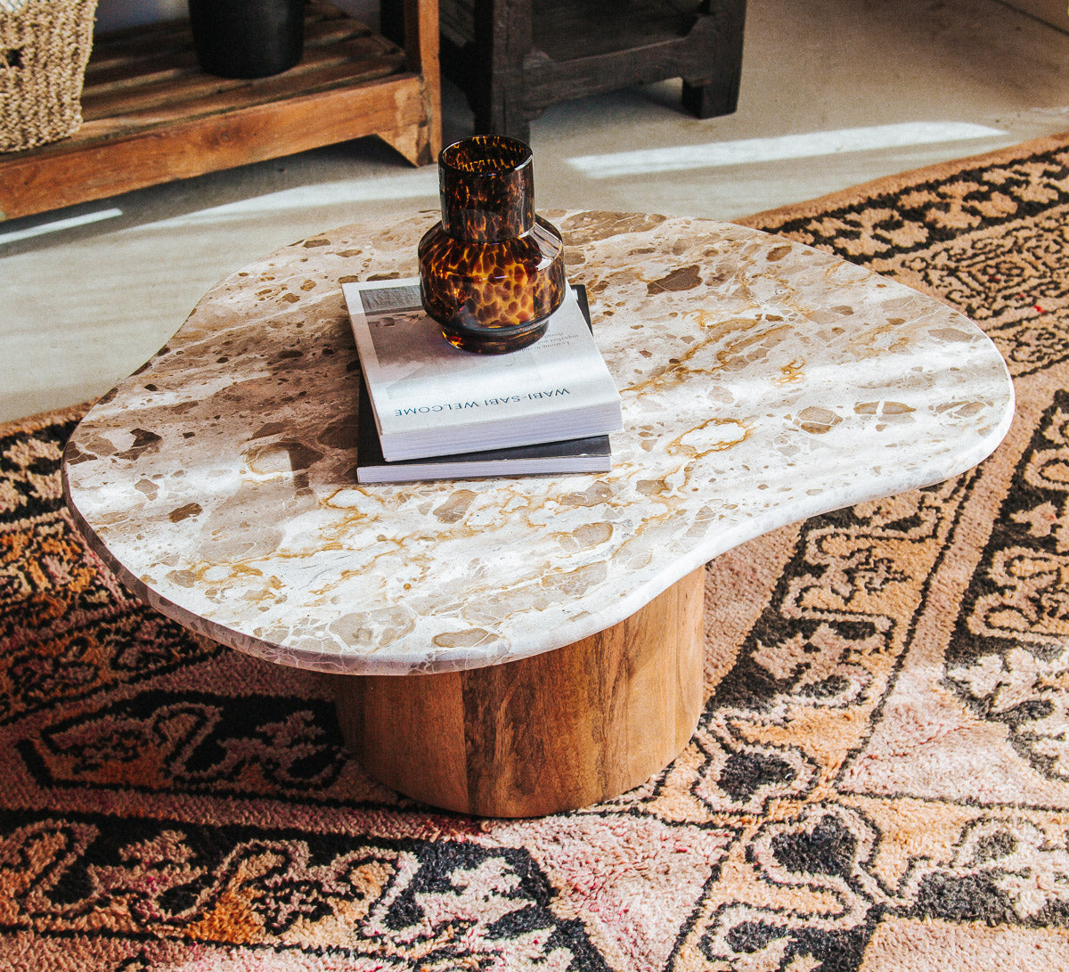 boho designer avi marble coffee table in an organic shape with a round curved solid wood base