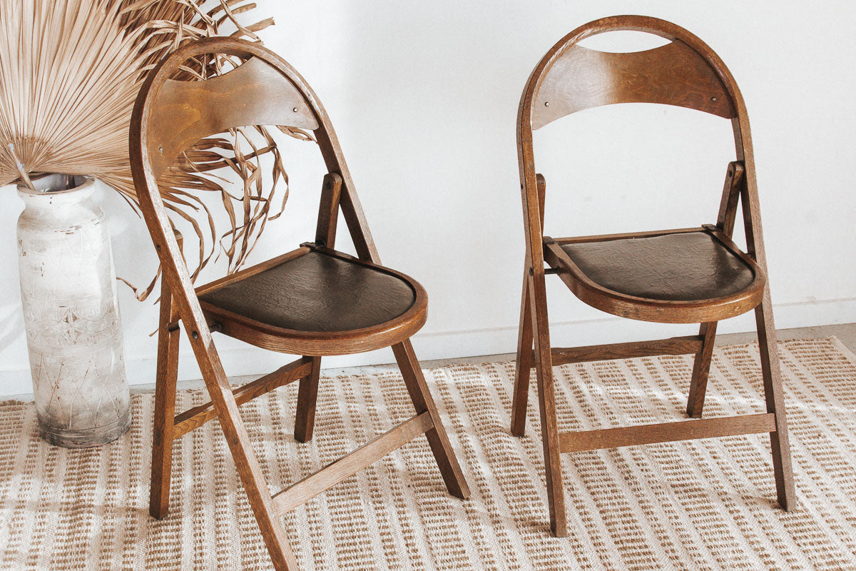 Vintage wooden folding chair with carved seat detail, inspired by antique Storkline design, styled as a decorative bedside piece.