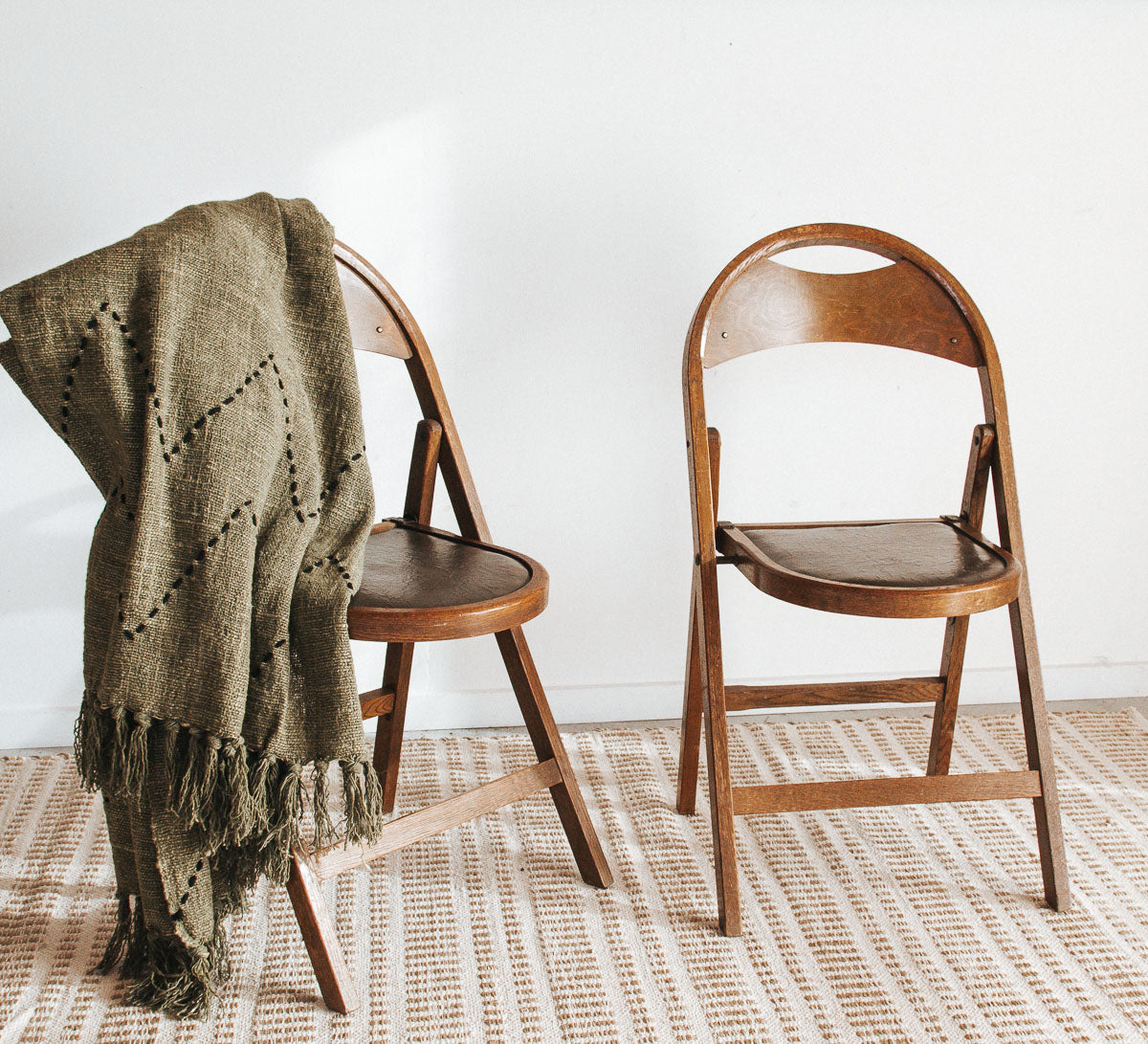 Vintage wooden folding chair with carved seat detail, inspired by antique Storkline design, styled as a decorative bedside piece