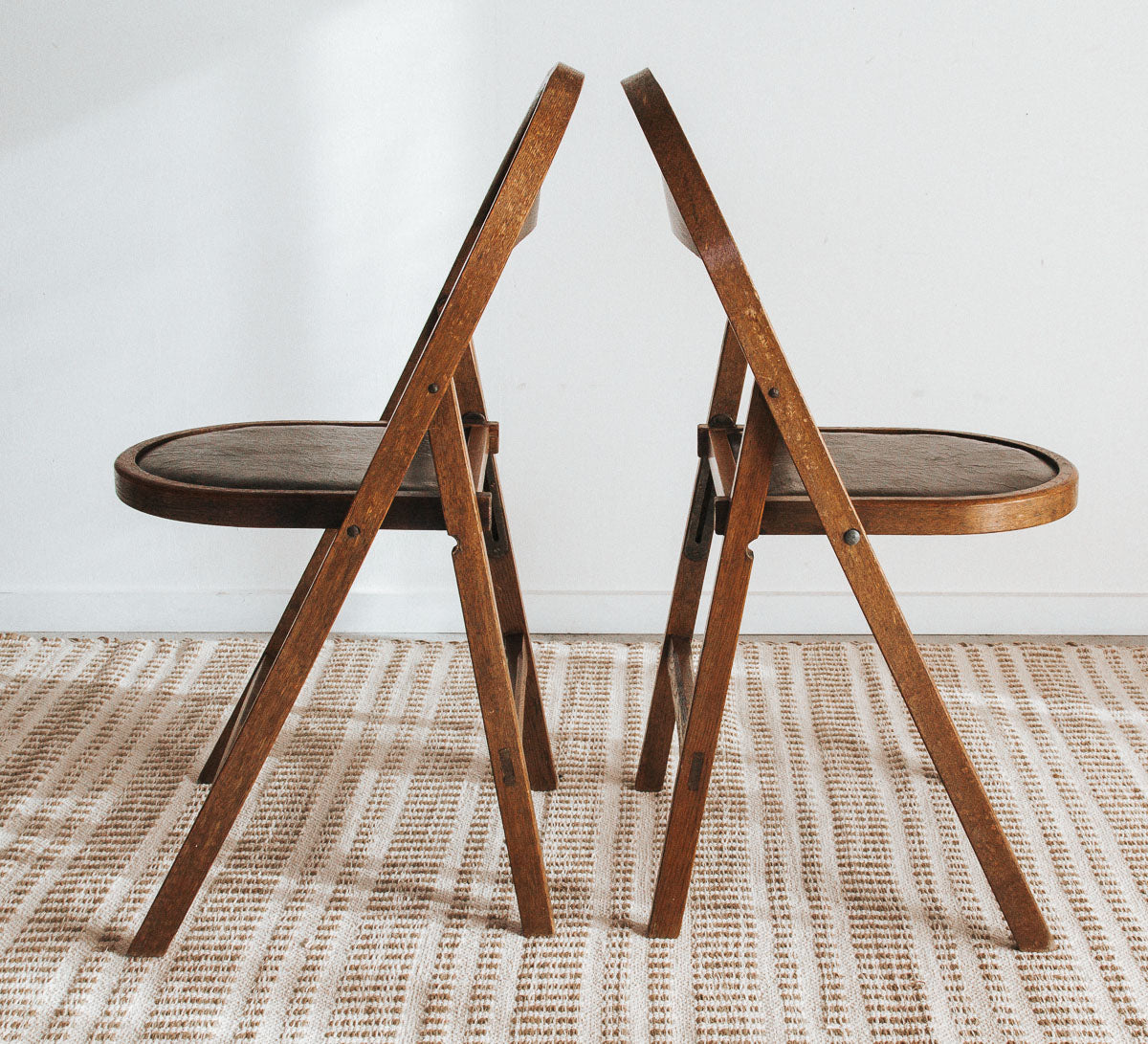 Vintage wooden folding chair with carved seat detail, inspired by antique Storkline design, styled as a decorative bedside piece.